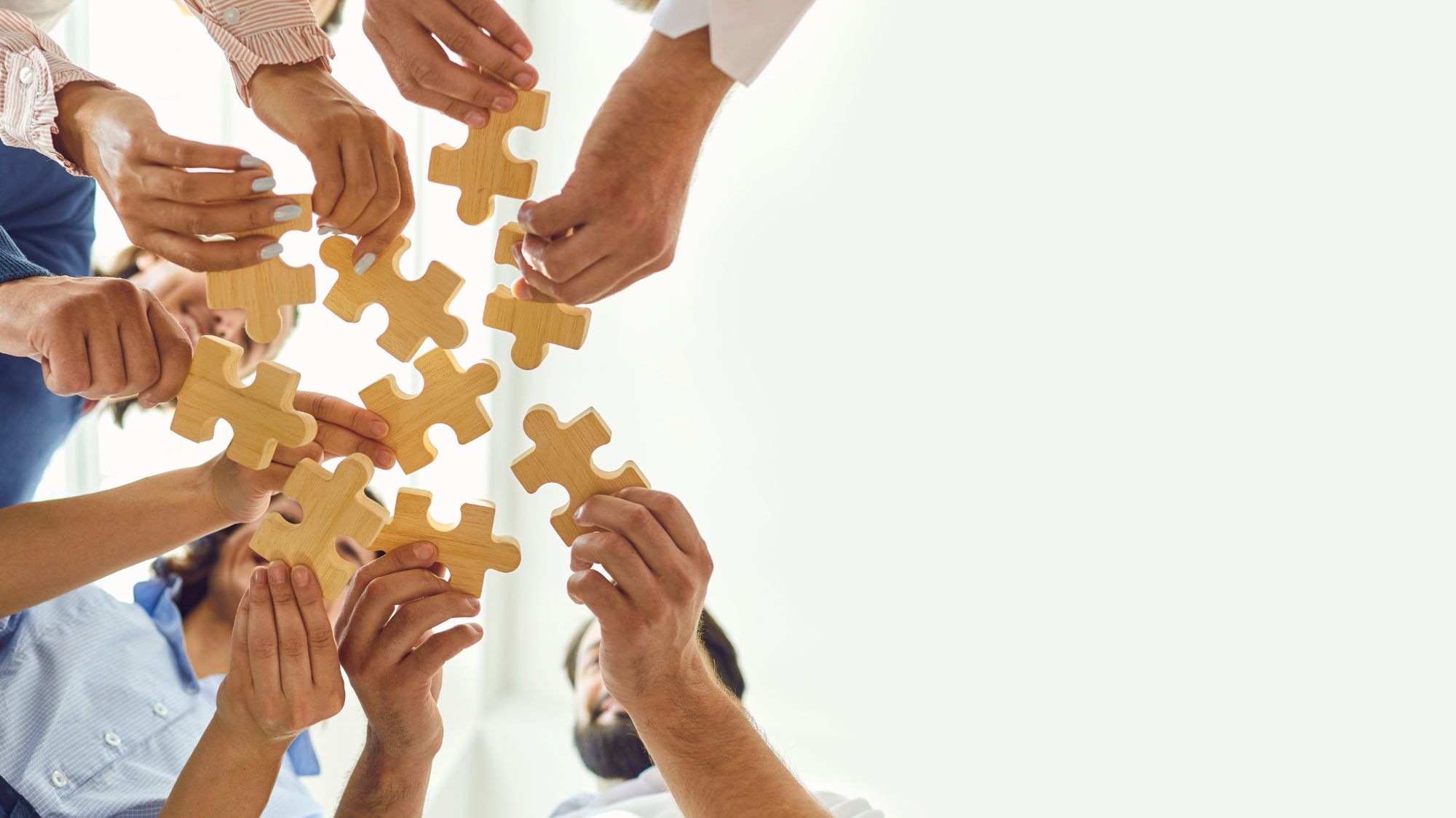 Image of hands in a circle all holding pieces of a jigsaw puzzle